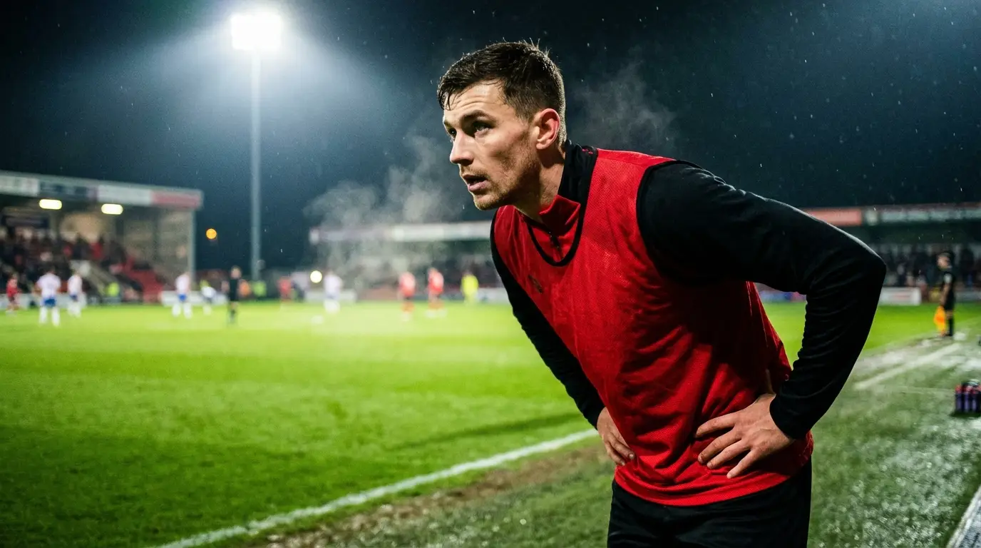 An atmospheric shot of a Thailand U23 substitute player on the sidelines, watching the match intently, ready to be called upon as a 'game changer', capturing the tension and anticipation of the bench.