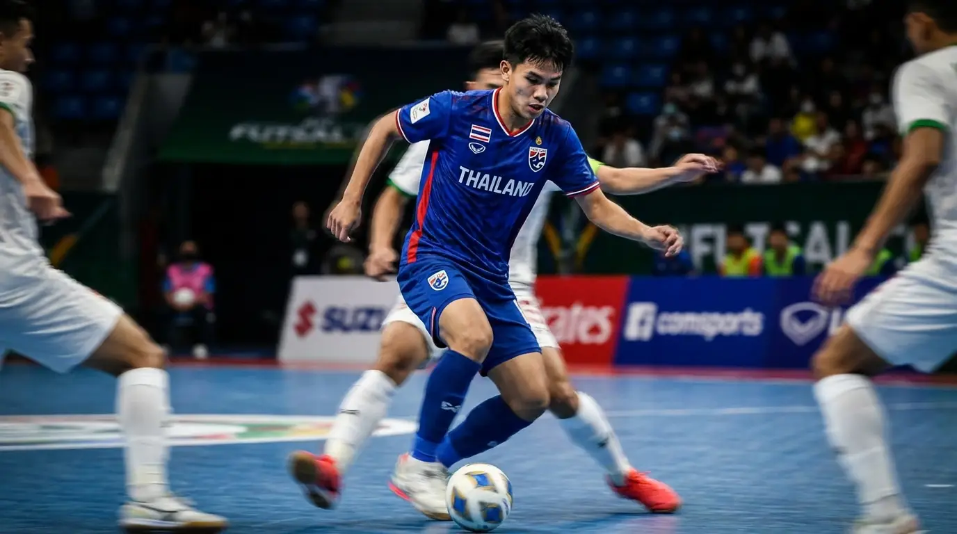 A young, agile futsal player in Thailand kit showcasing quick dribbling skills and close control in a tight space on court.